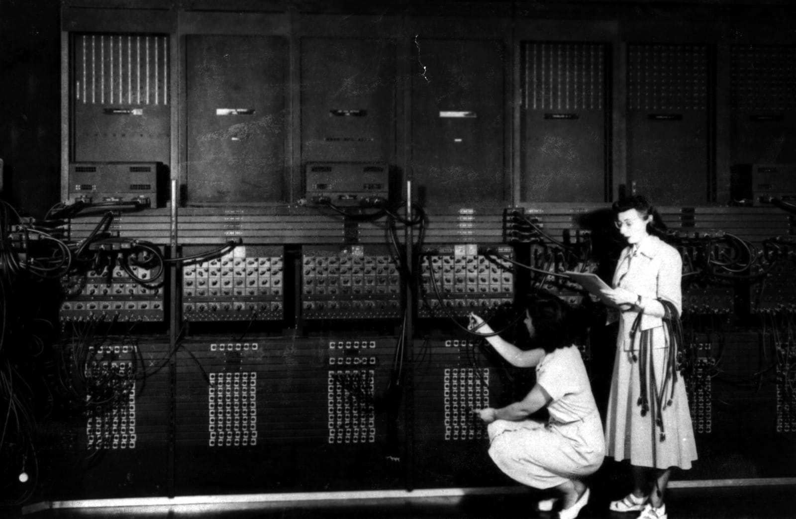 Deux personnes recâblent les panneaux de l’ENIAC pour un nouveau calcul