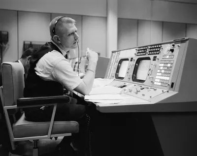 Eugene F. Kranz, directeur de vol, assis à son pupitre dans la salle des opérations de la mission, les mains jointes devant lui.