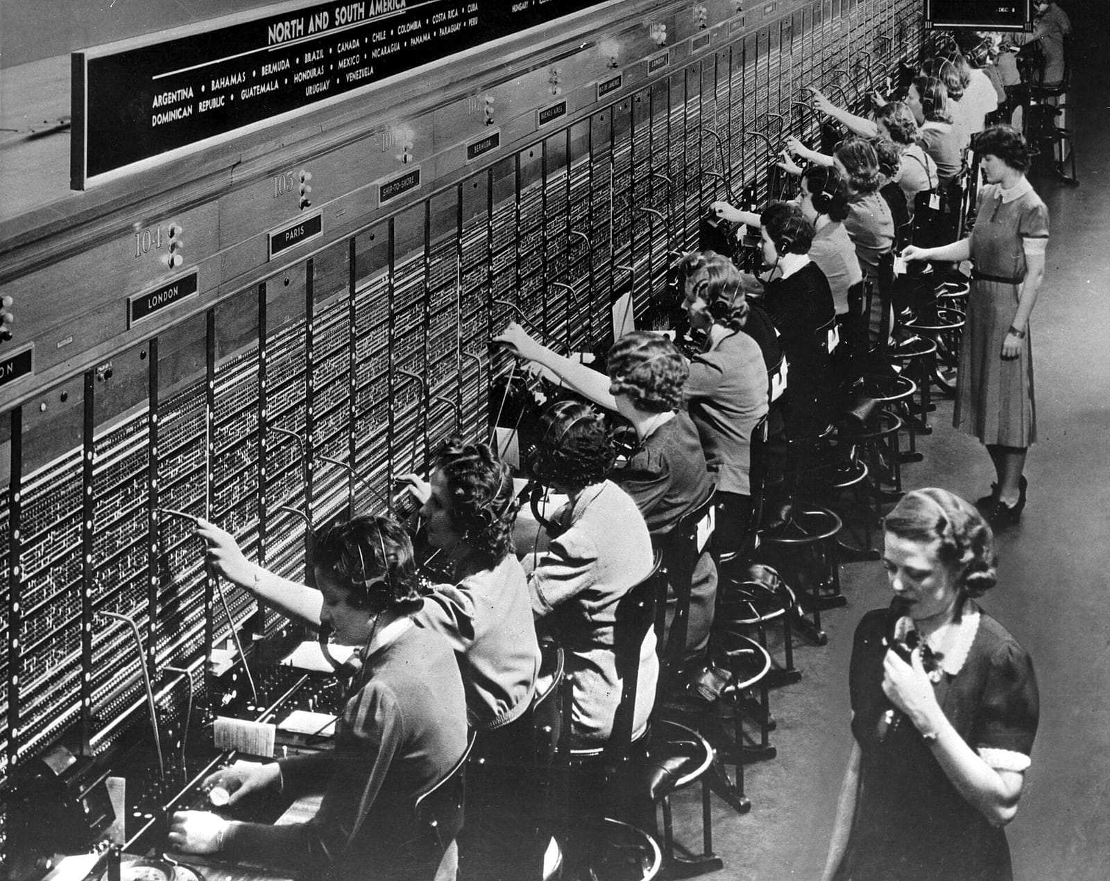 Une rangée d’opératrices branche des fiches sur un standard téléphonique du Bell System